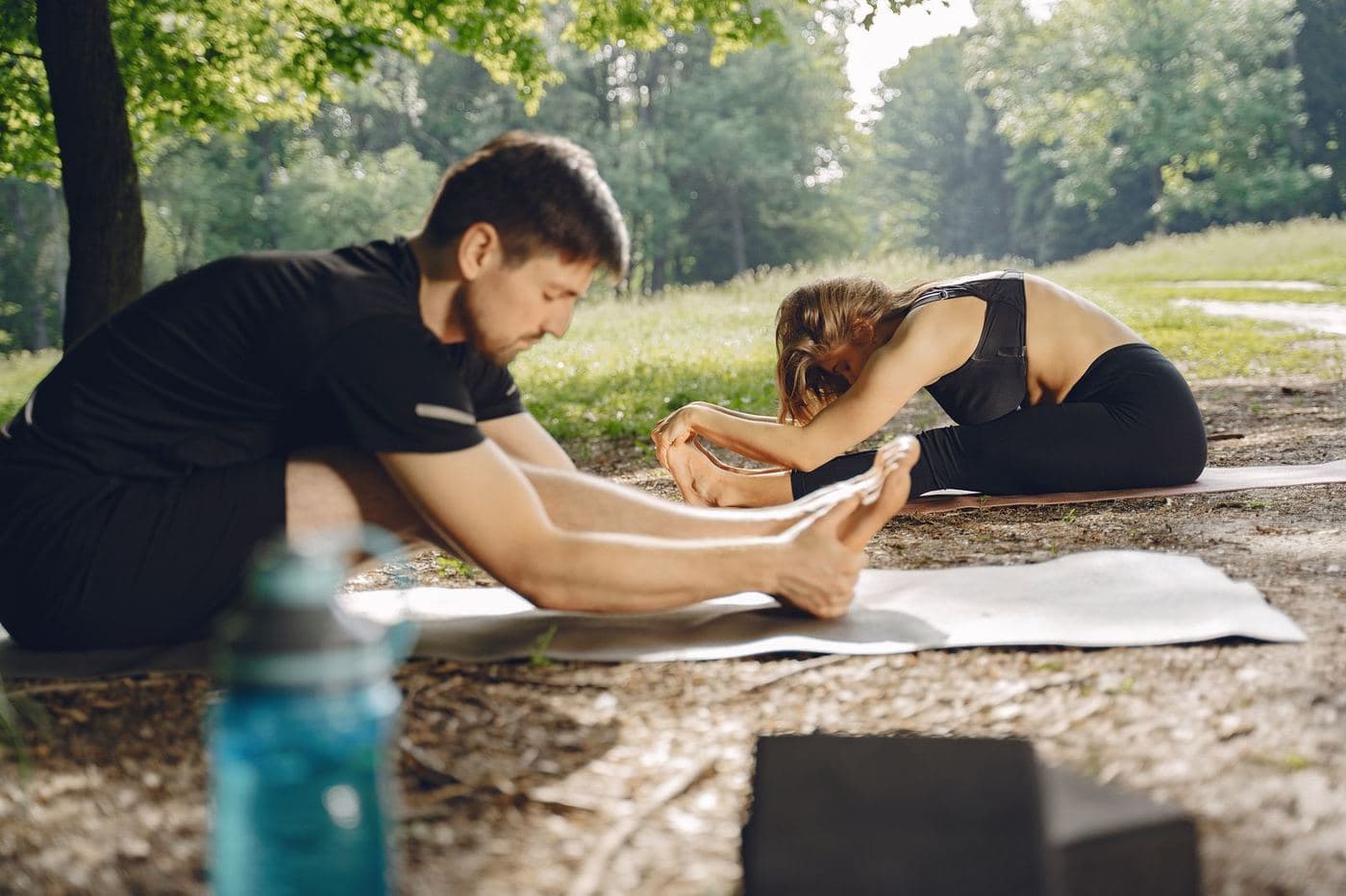 Older adults stretching on yoga mats in a sunny park