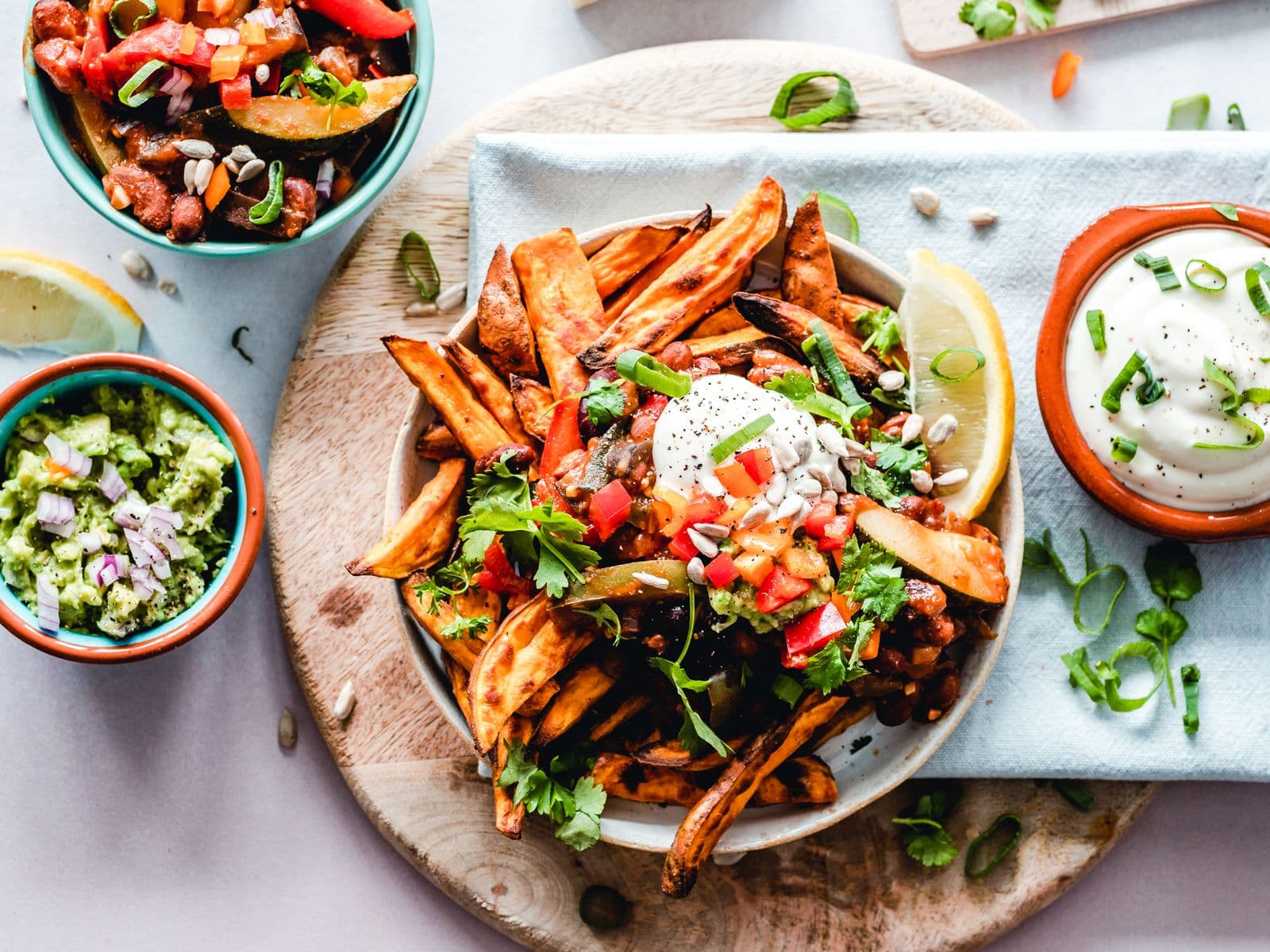Top view of a colorful plate of sweet potato fries and fresh toppings